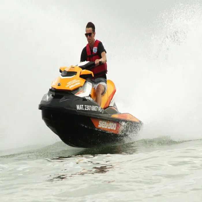 A tourist riding a Sea-Doo jet ski at high speed in the Cancun Hotel Zone turquoise waters.