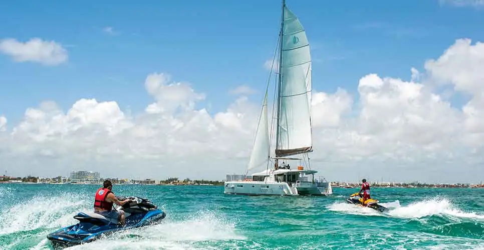 Jet Ski Cancun personal watercraft are sailing near a catamaran in the Bahia de Cancun