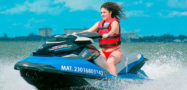 A beautiful young woman drives a jet ski in the sea, rented from Jet Ski Cancun