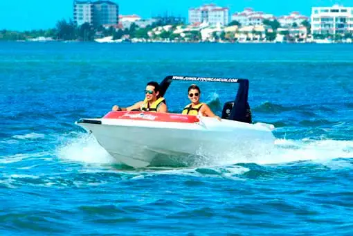 A couple cruises by speedboat in Cancun.