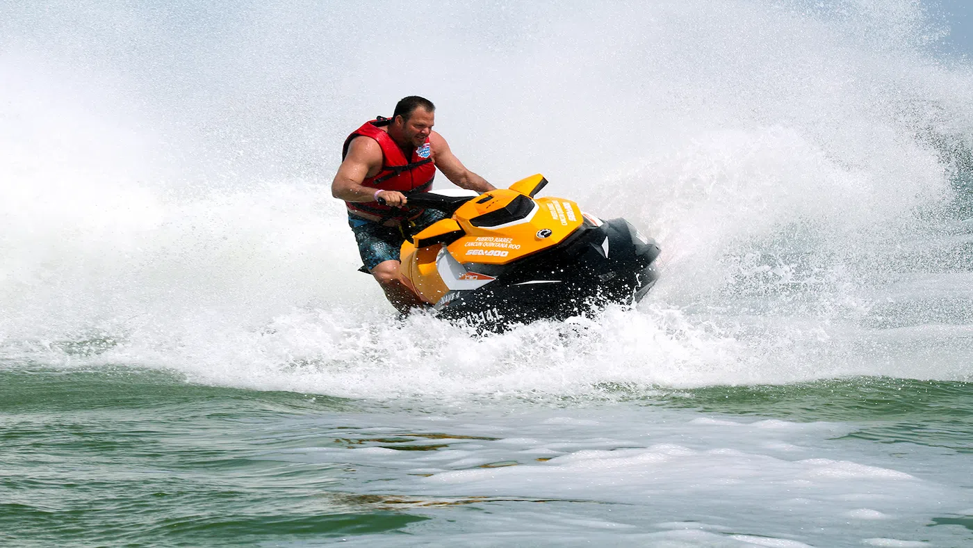 Man making a big splash while enjoying a fast and fun jet ski rental in Cancun.