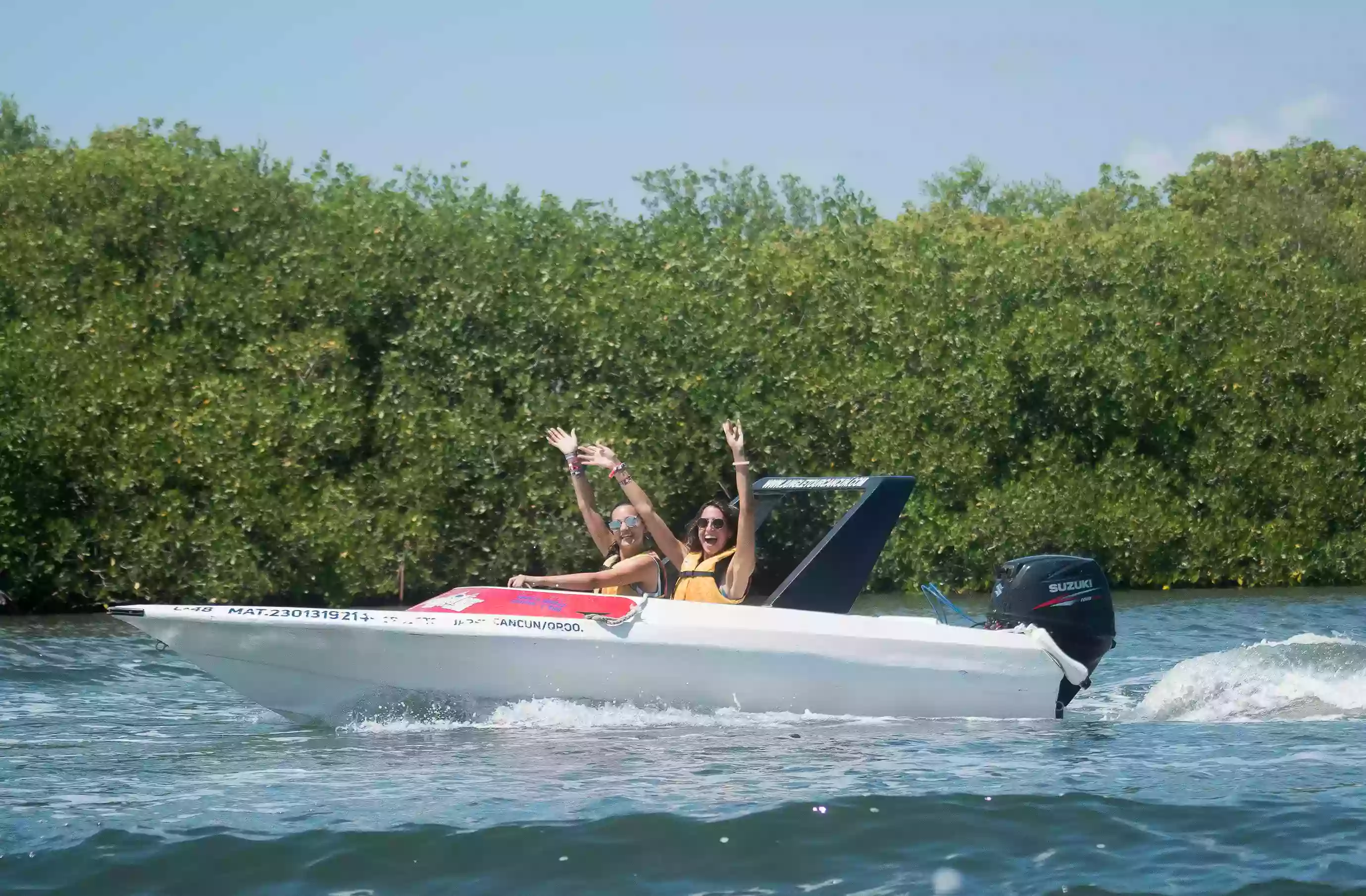 two very happy women aboard a Jungle Tour Adventure speedboat, sailing through the canals of the lagoon in Cancun.